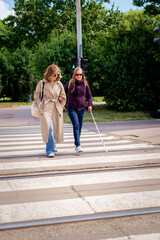 Visually impaired woman wlaking with female friend in the city in a windy day