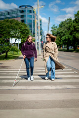 Visually impaired woman wlaking with female friend in the city in a windy day