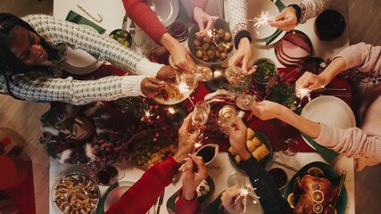 Hand lighting candles on dining table top view. Friends celebrating new year, delicious dishes, cooked homemade food on plates. Christmas party at home. - Powered by Adobe