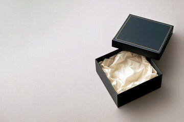 A luxurious open black gift box mockup with gold accents and lightly wrinkled tissue paper inside. This elegant, minimalist layout with plenty of room for text is perfect for luxury branding.