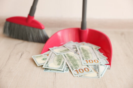 Dustpan with dollar banknotes and broom on wooden floor indoors, closeup - Powered by Adobe