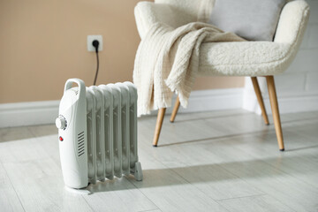 Electric heater on light wooden floor indoors