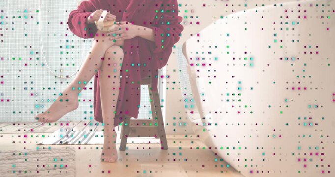 Woman wearing red bathrobe sitting beside bathtub picking up bristle brush for exfoliating leg