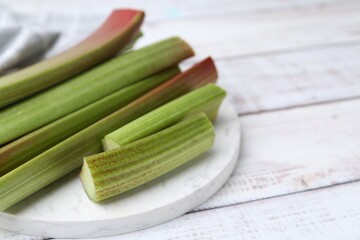 Rhubarb stalks on white wooden table, closeup. Space for text