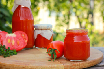 Homemade tomato sauce sits on a wooden stand outside. DIY country-style preserves. Organic food