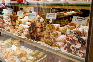 Close-up of a Retail Display Window Filled with Traditional Sicilian Cannoli with Various Fillings and Powdered Sugar in a Venetian Pasticceria