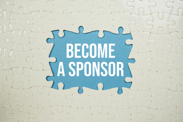 Jigsaw puzzle with a missing piece with "Become a Sponsor" on blue background