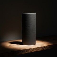 Minimalist dark ceramic cylinder vase with subtle texture on a rustic wooden surface