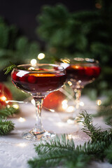 Christmas cocktails in couple glasses with bokeh lights and fir branches. Christmas mood. Shallow depth of field.