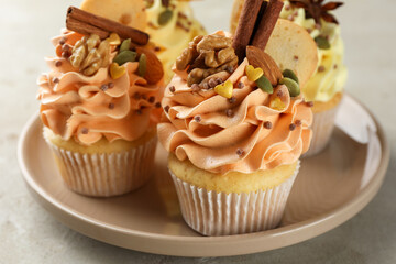 Delicious cupcakes with colorful cream, spices and nuts on grey table, closeup