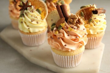 Delicious cupcakes with colorful cream, spices and nuts on grey table, closeup