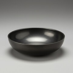 A simple dark gray ceramic bowl with a subtle textured rim against a neutral gray background