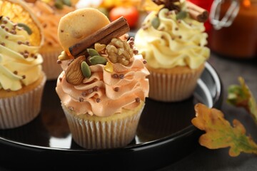 Delicious cupcakes with sprinkles, nuts, cookie and spices on grey table, closeup. Autumn atmosphere