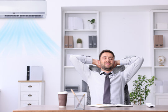 Worker under air conditioner in office. Keeping comfortable temperature