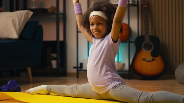 Adorable little girl doing side split, preparing for gymnastics competition