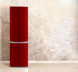 Red refrigerator near beige textured wall in room