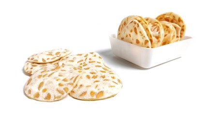 Front view of Keripik Tempe or Tempeh Chips in white bowl. Isolated on white background with copy space. Traditional Indonesian food are made from soybeans mixed with rice flour then sliced ​​thinly.