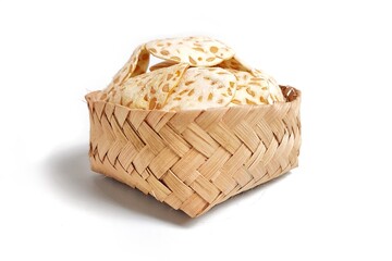 Front view of Keripik Tempe or Tempeh Chips in bamboo basket. Isolated on white background. Traditional Indonesian food are made from soybeans mixed with rice flour then sliced ​​thinly. 