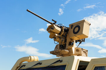 Heavy machine gun. Weapon on the top. Armament and weaponry in military army. Blue sky with clouds as copy space.
