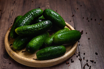 Fresh cucumbers on a round wooden plate