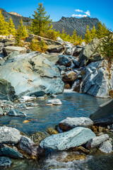 A mountain stream of clear, azure water against the backdrop of a mountain valley in the Alps
