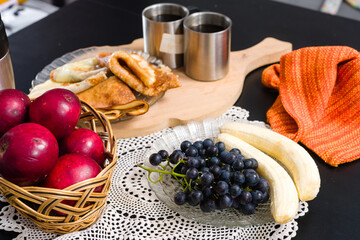 Breakfast table with pancakes, fruit, and hot drinks.