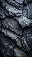 Vertical image of layered, dark gray stone with subtle gold accents