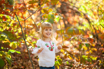 Joyful Girl Enjoying a Sunny Autumn Day Among Colorful Leaves in a Forest as Halloween Approaches in October