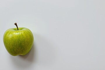 Single green apple on white surface with ample negative space, highlighting freshness, simplicity, and modern visual balance.