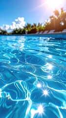 Sparkling blue pool water reflecting sunlight, with palm trees and sky blurred in the background