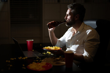 Overworked businessman works late at night on his laptop. Busy employee overworked in office work during a late-night. Hispanic Freelancer overworked in late night. Deadline and overwork concept.