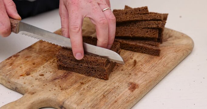 fresh black rye bread cut for croutons on a cutting board, pieces of fresh soft sliced bread made from rye flour , bread for frying in oil with spices