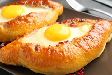 Tasty khachapuris with cheese and eggs on grey table, closeup