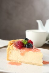 Piece of tasty cheesecake with berries and sauce on table, closeup