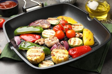 Pan with grilled vegetables and spices on grey table, closeup
