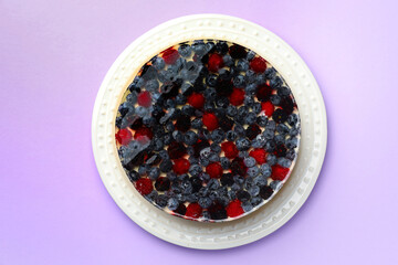 Delicious cheesecake with berries on violet background, top view
