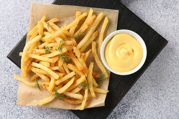 Tasty french fries with sauce on light grey table, top view