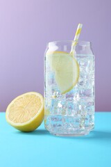 Refreshing lemon water with ice in glass and fresh citrus fruits on color background