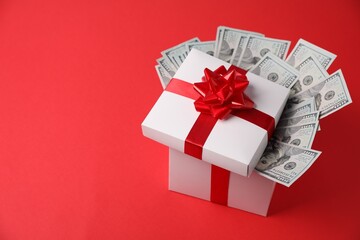 Gift box with dollar banknotes on red background. Space for text