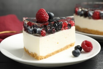 Piece of delicious cheesecake with berries on black wooden table, closeup