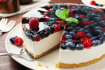 Taking piece of delicious cheesecake with berries at wooden table, closeup