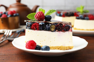 Piece of delicious cheesecake with berries and mint served on wooden table, closeup