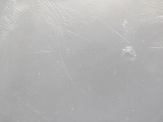A light gray textured background. A transparent, worn plastic bag with with subtle scratches and imperfections.
