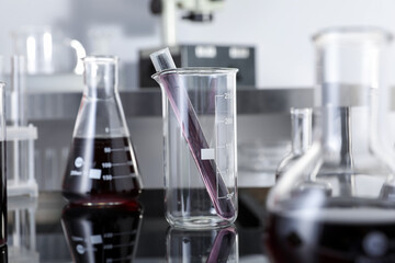 Different glassware with red liquid on table in laboratory, selective focus