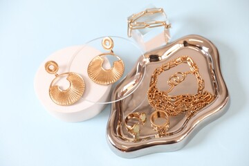 Beautiful gold jewelry on light blue background, closeup