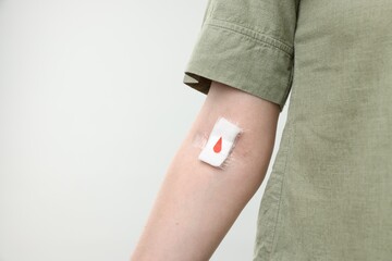 Blood donation. Woman with bandage on arm against light background, closeup. Space for text