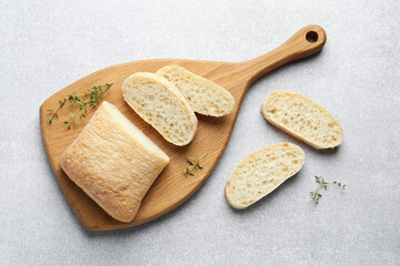 Cut crispy ciabatta and thyme on light grey table, flat lay