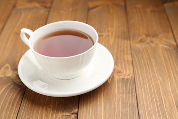 Cup of aromatic black tea on wooden table, closeup. Space for text