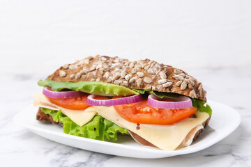 Tasty ciabatta sandwich with cheese and vegetables on white marble table, closeup