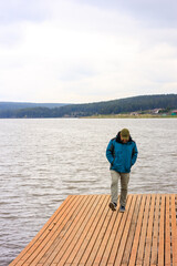 A man is walking on a dock near a body of water